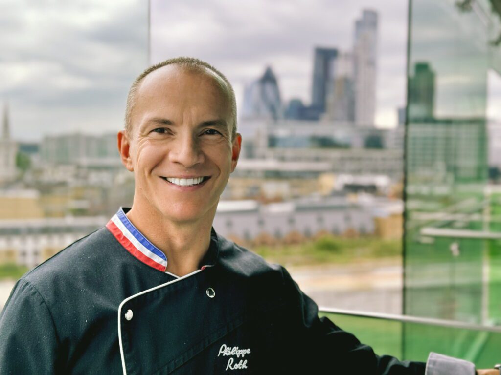 A man in chef 's outfit smiling for the camera.