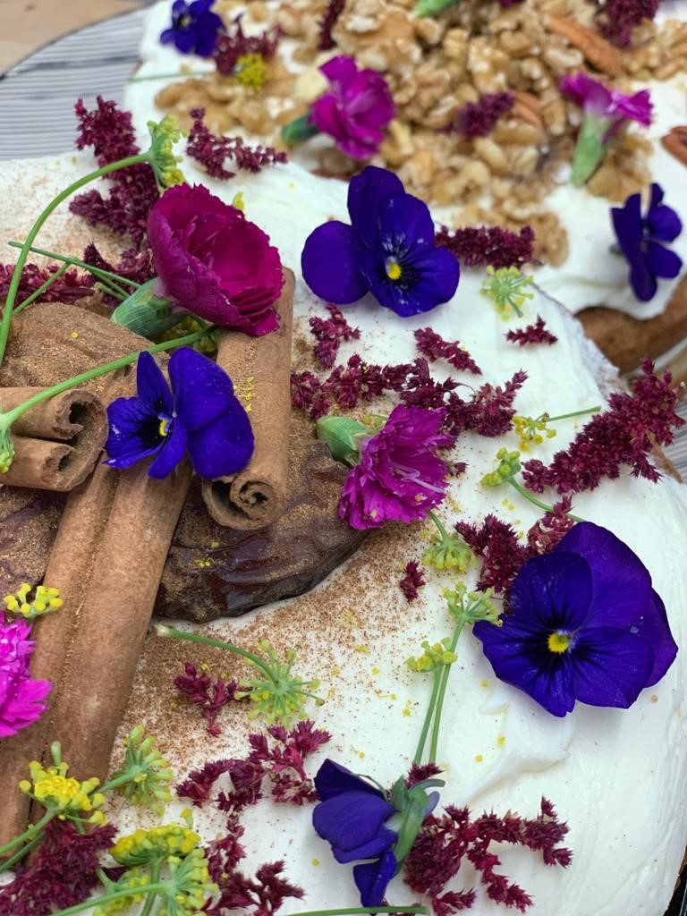 A cake with flowers and cinnamon sticks on top.