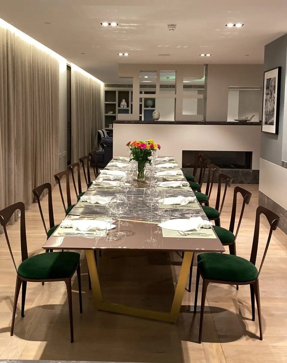 A long table with green chairs and white plates